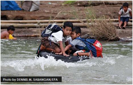 Students use an inflated tube to cross this swollen river on their way to school in a remote village in the Philippines’ Rizal province