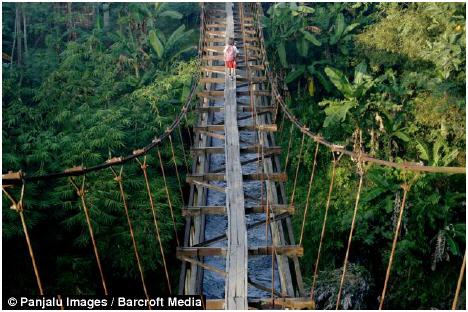 A school child crosses the aqueduct that separates Suro Village and Plempungan Village in Java, Indonesia