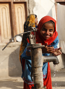 Children in Sindh, Pakistan, play at a water pump in a village